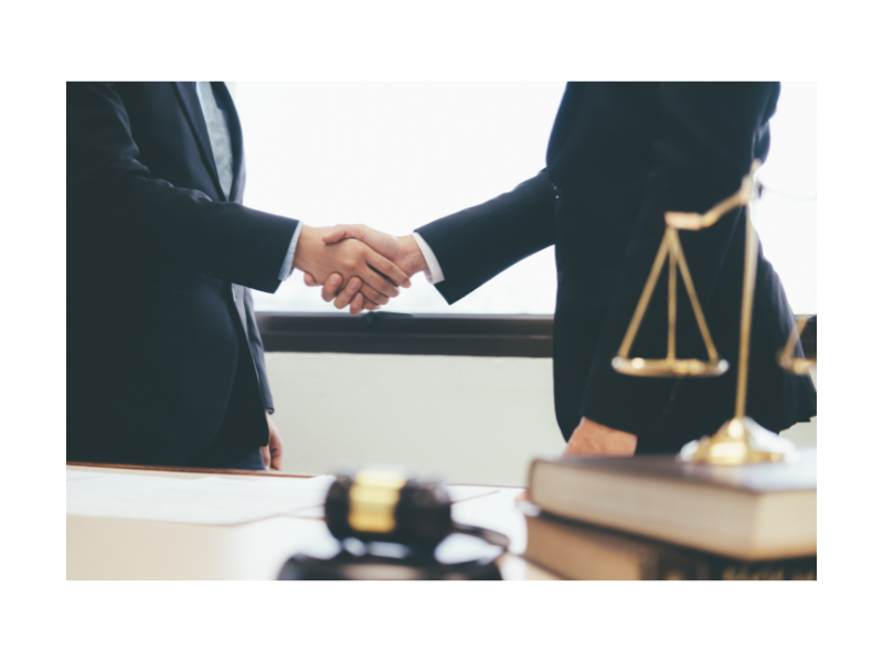 Two business professionals shaking hands over a desk, symbolizing collaboration at Headley Legal Support Services.